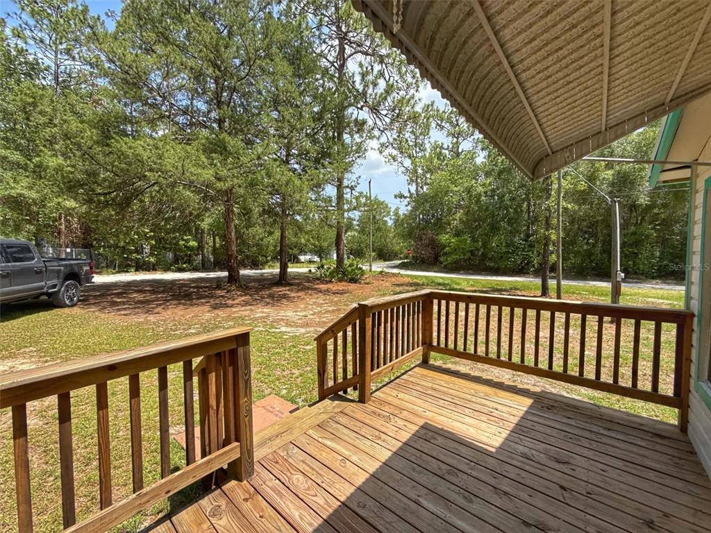 A wooden deck with railings overlooks a grassy yard and a wooded area — 65 NE 528TH AVENUE, OLD TOWN, FL