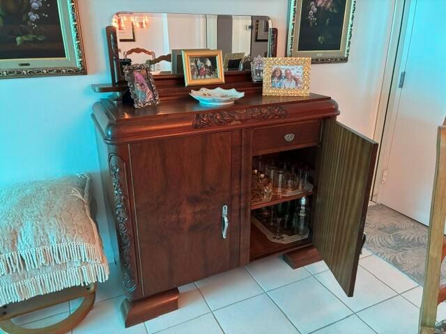 A wooden sideboard with an attached mirror stands in a room with tiled floors — 101 Briny Avenue # 707, Pompano Beach FL 33062, POMPANO BEACH, FL
