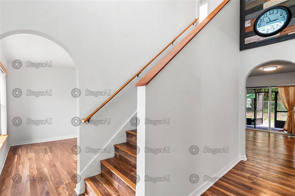 A staircase with wooden treads and a handrail sits between two arched doorways — 803 MOUNTBATTEN LANE, KISSIMMEE, FL
