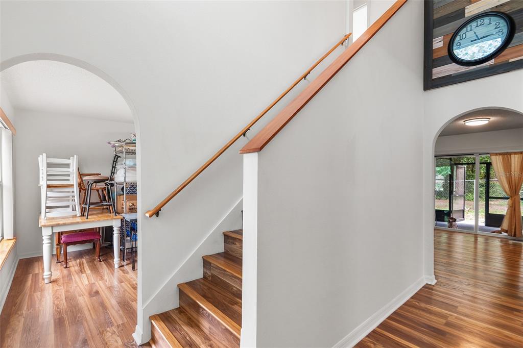 A staircase with wooden steps and a handrail sits between two arched doorways — 803 MOUNTBATTEN LANE, KISSIMMEE, FL