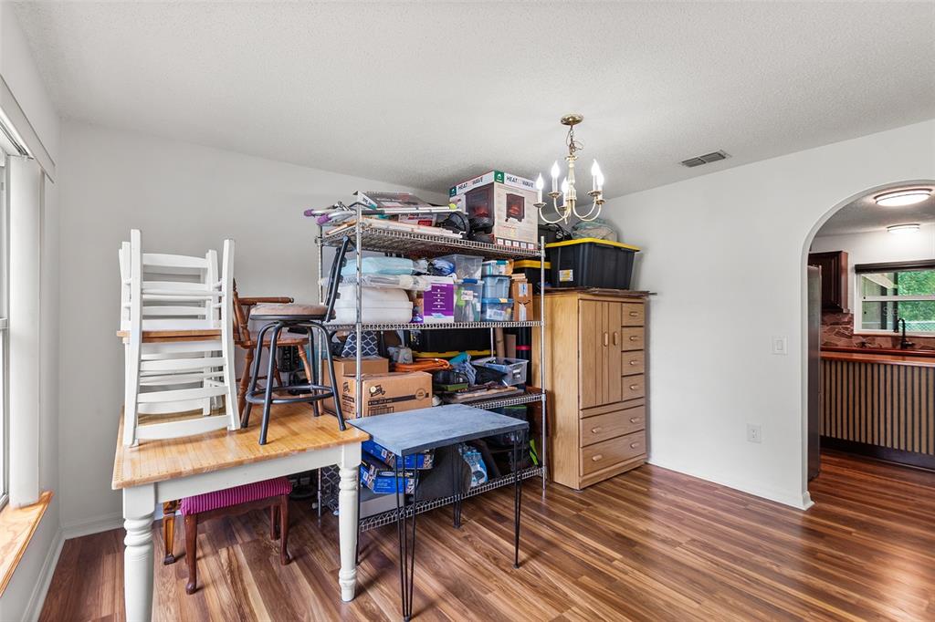 A dining room with wood-look flooring, a metal storage rack, and a wooden cabinet — 803 MOUNTBATTEN LANE, KISSIMMEE, FL