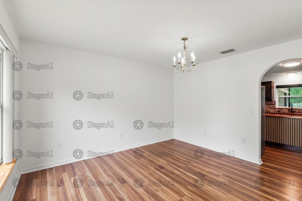An empty dining room features white walls, wood-look flooring, and a traditional chandelier — 803 MOUNTBATTEN LANE, KISSIMMEE, FL