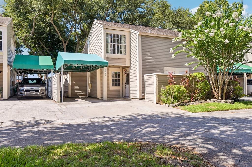 A two-story house with light gray siding, a green carport, and a white front door — 6910 LAKE PLACE COURT, TAMPA, FL