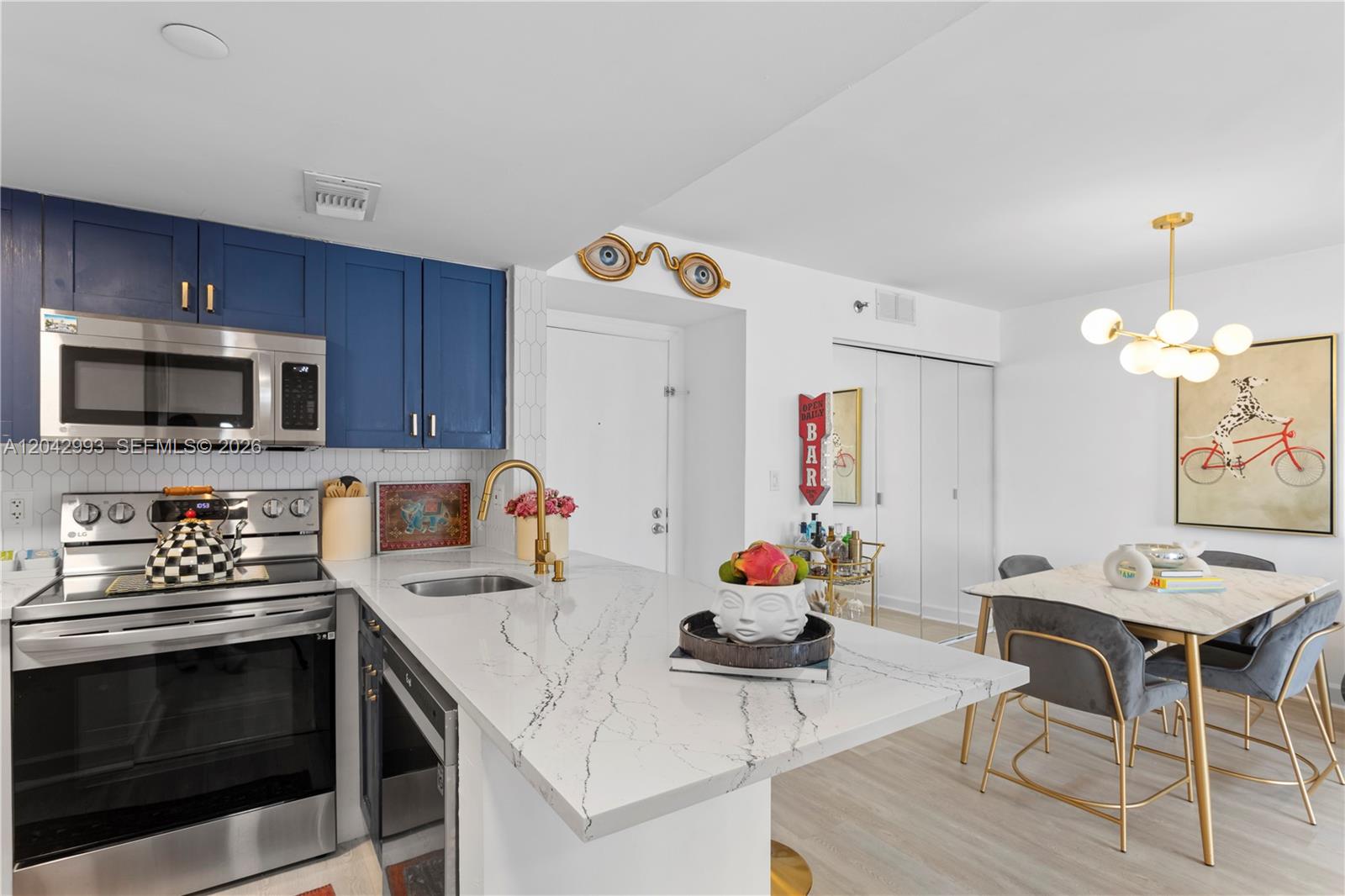 A modern dining area and kitchen feature white cabinetry, gold accents, and a chess set — 770 Claughton Island Dr # 1705, Miami FL 33131, MIAMI, FL