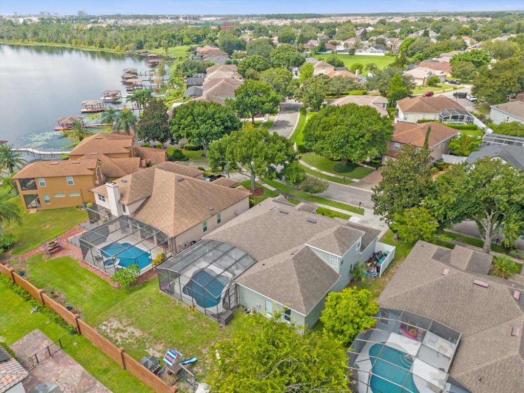 An aerial view shows several suburban houses with swimming pools near a large lake — 10175 COVE LAKE DRIVE, ORLANDO, FL