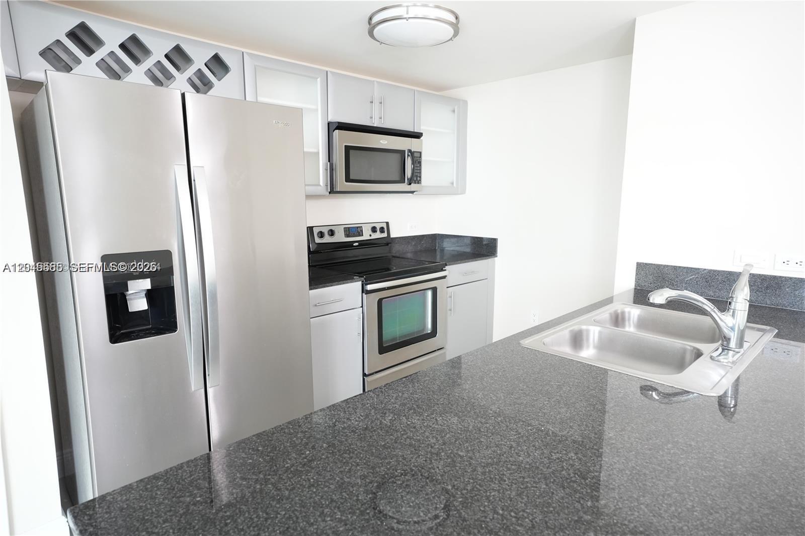 A kitchen features stainless steel appliances, grey cabinetry, and dark granite countertops — 1861 NW S River Dr # 2503, Miami FL 33125, MIAMI, FL
