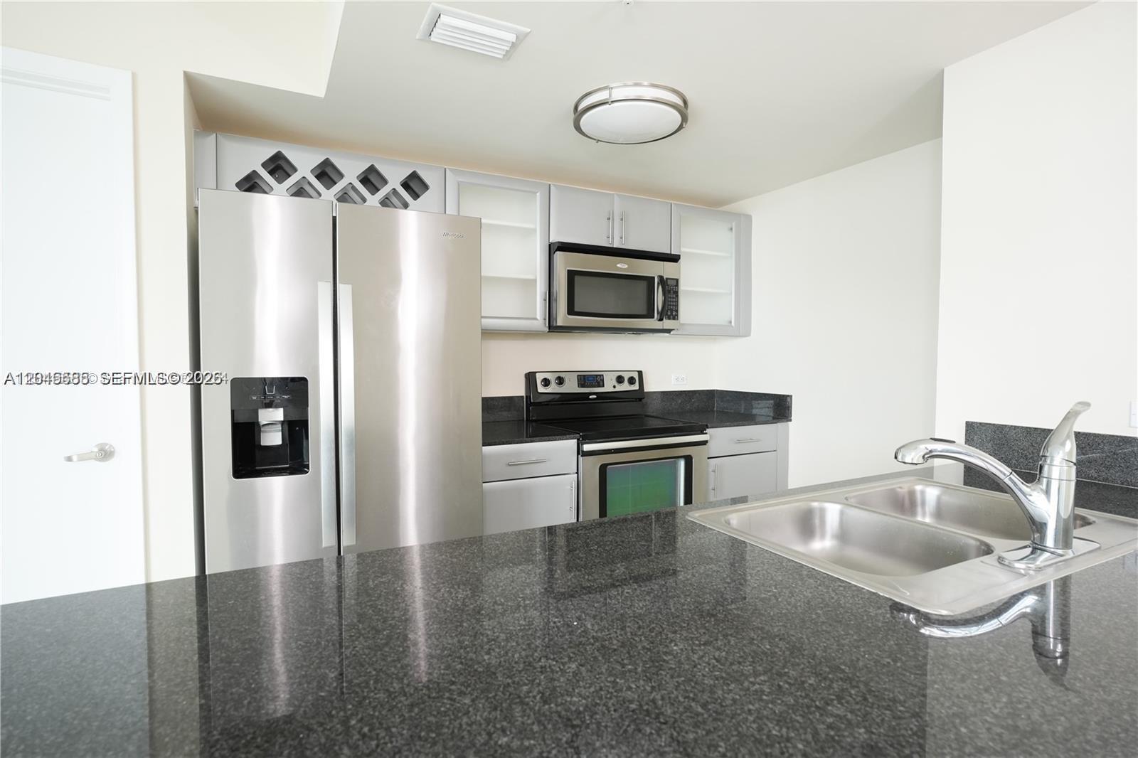A kitchen features stainless steel appliances, grey cabinetry, and dark granite countertops — 1861 NW S River Dr # 2503, Miami FL 33125, MIAMI, FL