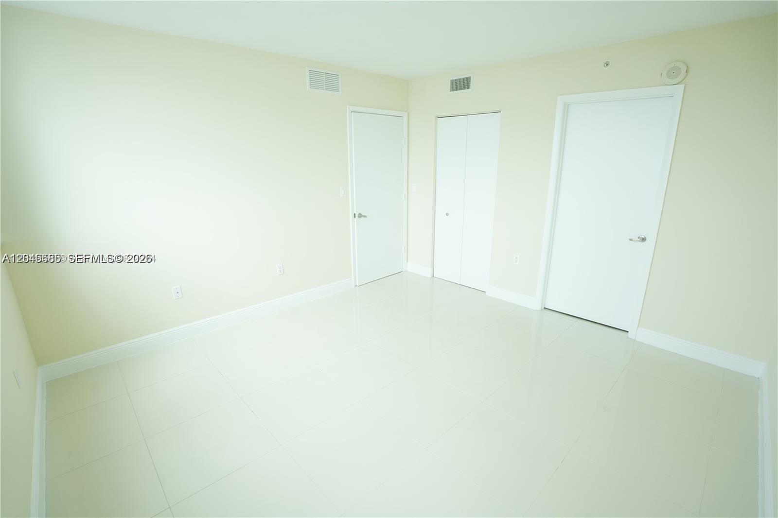 An empty room features light-colored walls, white doors, and glossy tile flooring — 1861 NW S River Dr # 2503, Miami FL 33125, MIAMI, FL