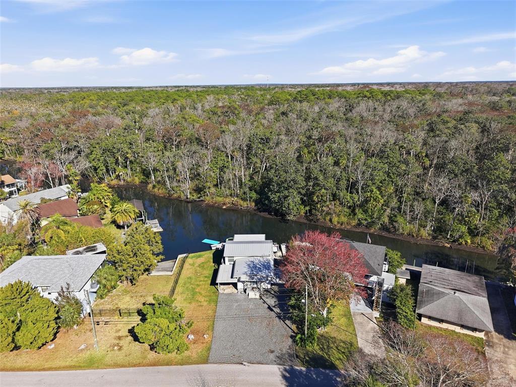 An aerial view shows a house with a gravel driveway situated along a riverbank — 7266 TROPICAL DRIVE, WEEKI WACHEE, FL