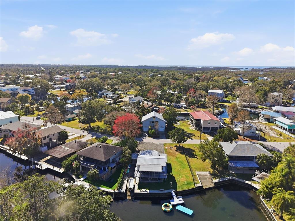 An aerial view shows waterfront houses with docks along a canal in a wooded area — 7266 TROPICAL DRIVE, WEEKI WACHEE, FL