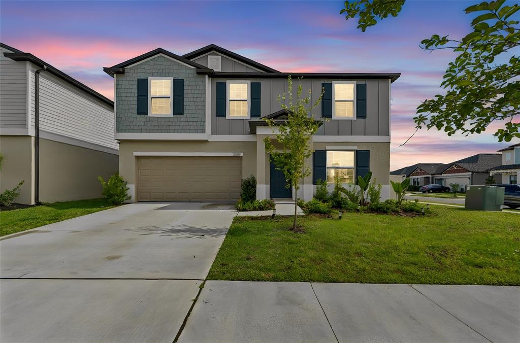 A two-story suburban house with a tan stucco exterior, gray siding, and a concrete driveway — 22203 CALISTO WAY, LAND O LAKES, FL