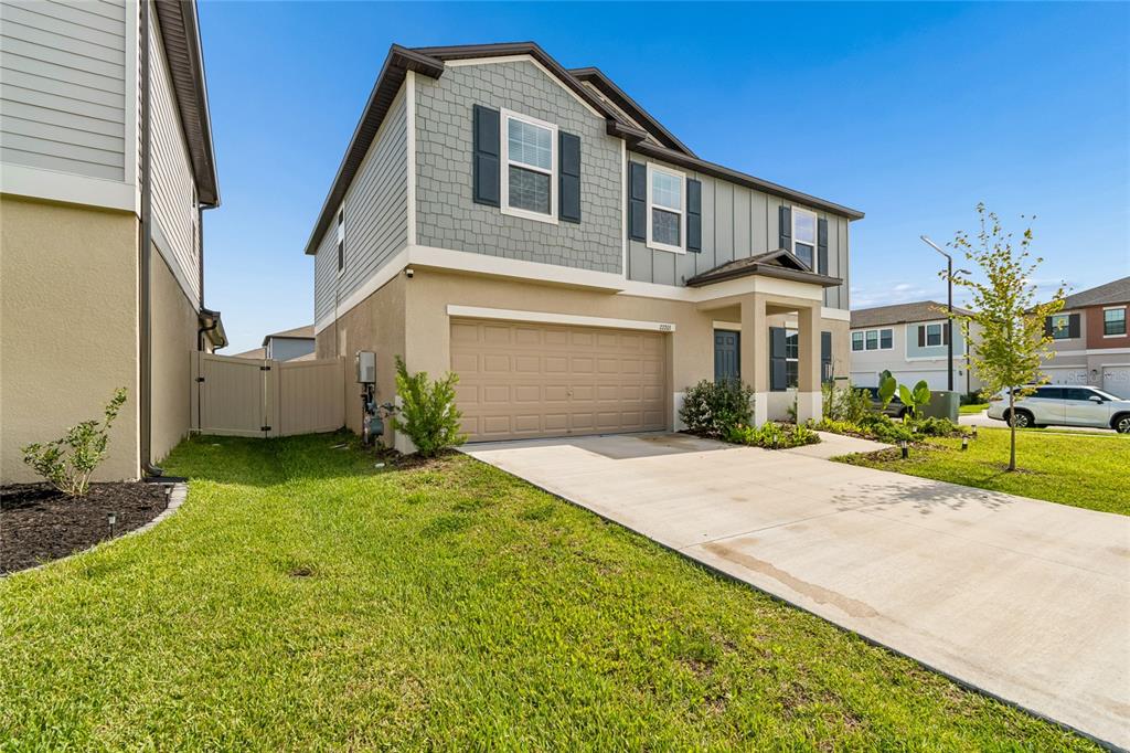 A two-story suburban house with a tan stucco lower level, gray shingle siding, and garage — 22203 CALISTO WAY, LAND O LAKES, FL