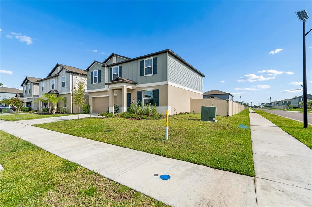 A two-story suburban house with a tan stucco and gray siding exterior and attached garage — 22203 CALISTO WAY, LAND O LAKES, FL
