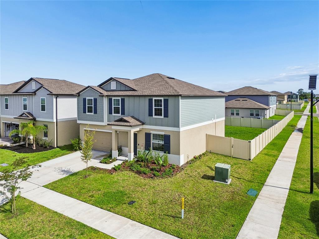 An exterior view of a two-story suburban house with a tan stucco and gray siding — 22203 CALISTO WAY, LAND O LAKES, FL