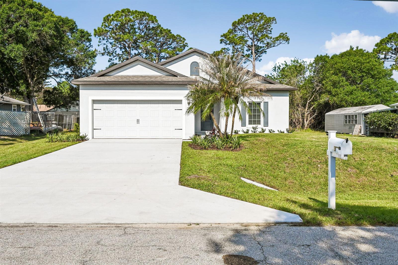 A white single-story house with a two-car garage, a palm tree, and a mailbox — 5901 Raintree Trail, Fort Pierce FL 34982, FORT PIERCE, FL