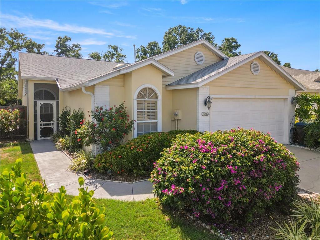 A single-story house with yellow siding, a two-car garage, and a front walkway — 7716 GENEVA LANE, SARASOTA, FL