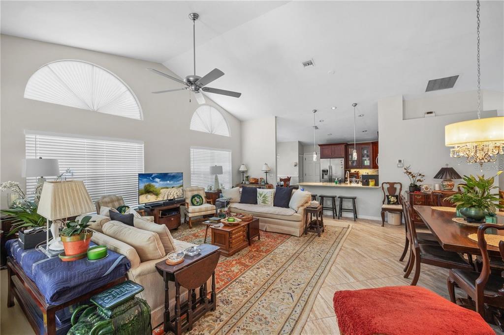 A spacious open-concept living and dining area with vaulted ceilings and tile flooring — 7716 GENEVA LANE, SARASOTA, FL