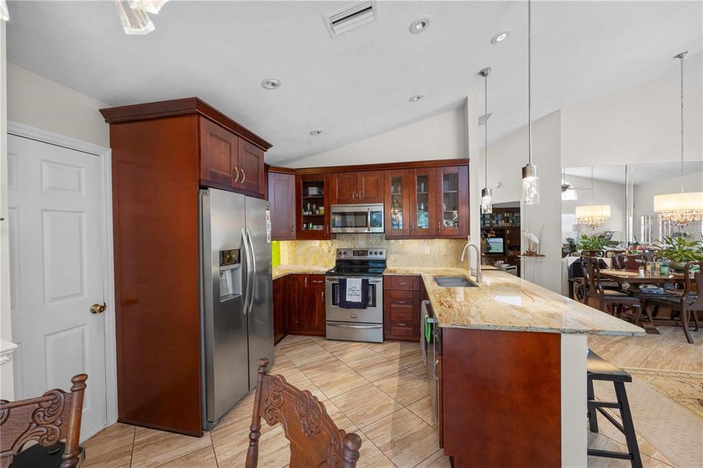 A kitchen features wood cabinets, granite countertops, stainless steel appliances, and tile flooring — 7716 GENEVA LANE, SARASOTA, FL