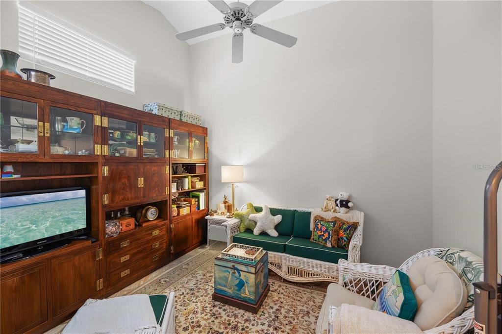 A living room features a large wooden entertainment center, a green sofa, and a ceiling fan — 7716 GENEVA LANE, SARASOTA, FL