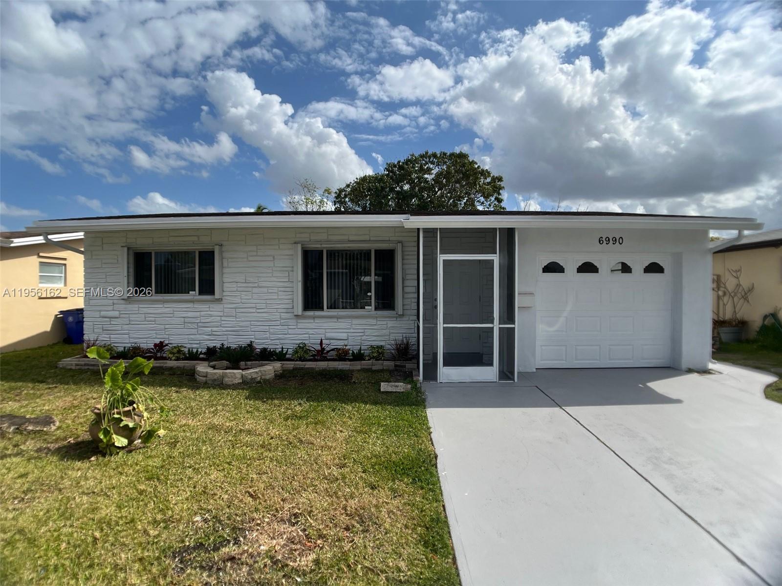A single-story house features white stone siding, a screened entryway, and a one-car garage — 6990 NW 17th St, Margate FL 33063, MARGATE, FL