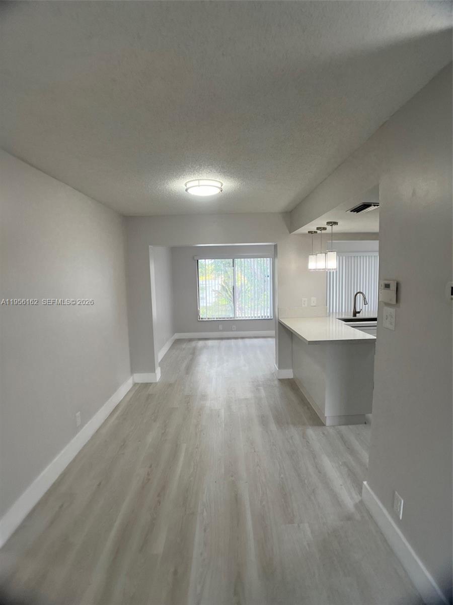 This room features light wood-look flooring, a kitchen breakfast bar, and a windowed dining area — 6990 NW 17th St, Margate FL 33063, MARGATE, FL