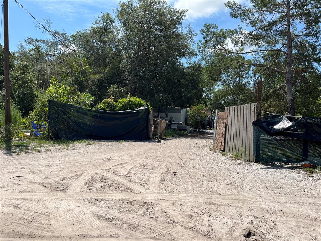 A sandy driveway leads toward a fenced area with trees and a small structure — 42334 W LAKE ROAD, DELAND, FL