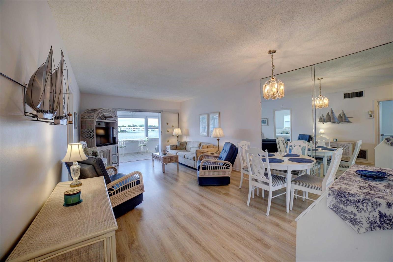 A living and dining area with light wood floors, wicker furniture, and a mirrored wall — 1801 Ocean Drive # 201, Boynton Beach FL 33426, BOYNTON BEACH, FL