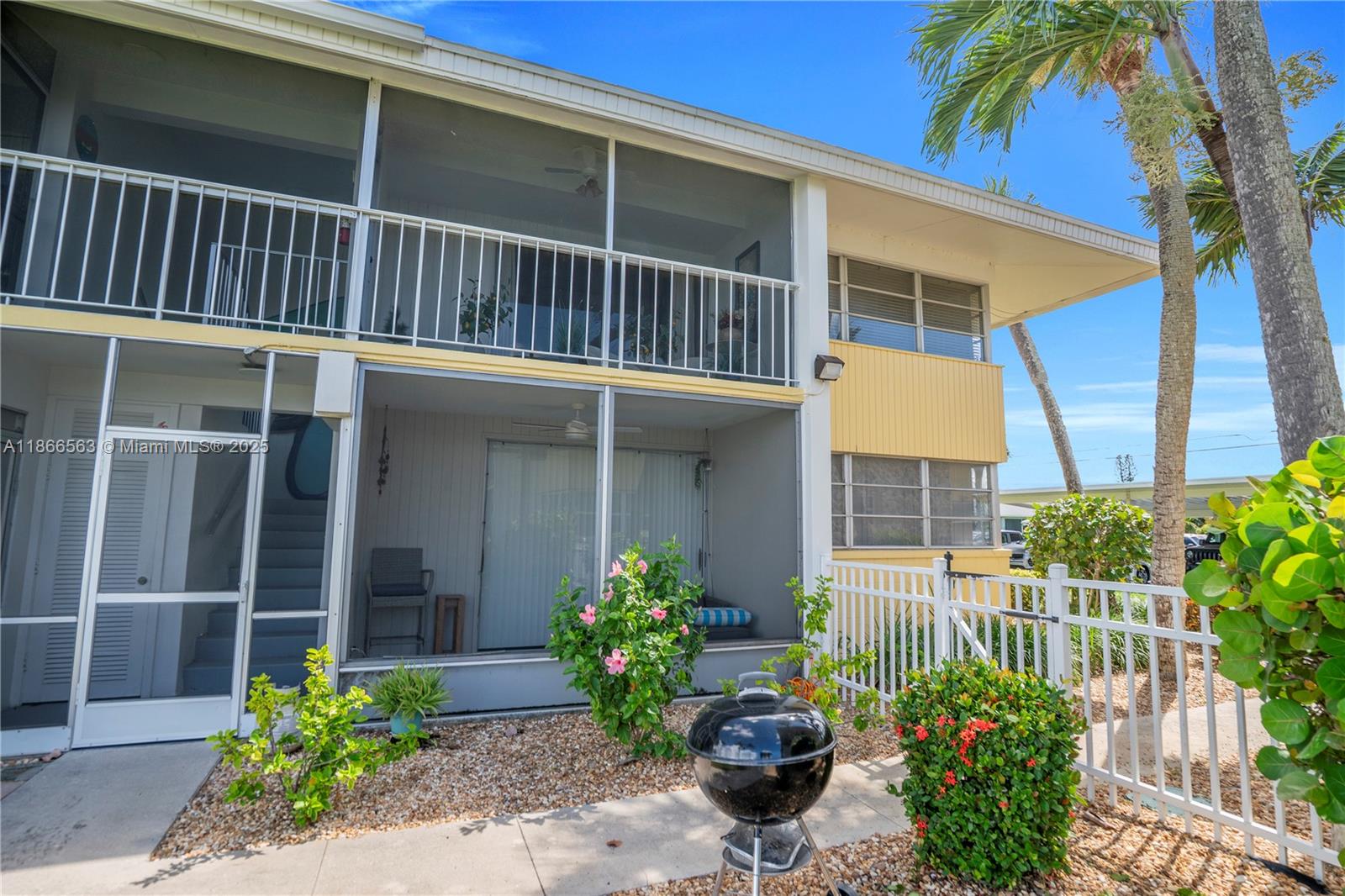 A two-story building features screened-in balconies, yellow siding, and a small patio with a grill — 4613 SE 5th ave # 210, Cape Coral FL 33904, CAPE CORAL, FL