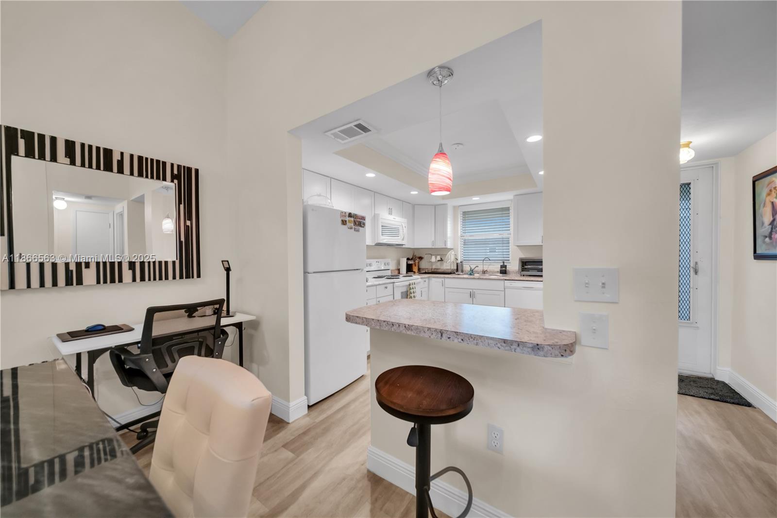 A kitchen with white cabinets and a breakfast bar opens into a dining area — 4613 SE 5th ave # 210, Cape Coral FL 33904, CAPE CORAL, FL