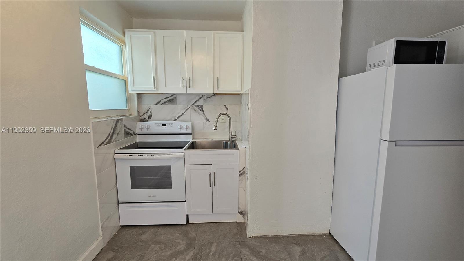 A small kitchen features white cabinets, a white stove, a sink, and a white refrigerator — 9680 NW 19th Pl, Sunrise FL 33322, SUNRISE, FL