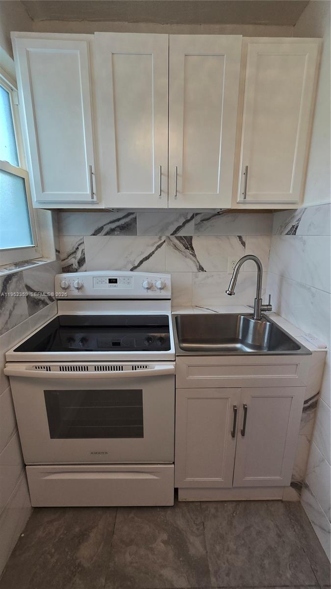 A small kitchen features white cabinets, a white electric stove, and a stainless steel sink — 9680 NW 19th Pl, Sunrise FL 33322, SUNRISE, FL