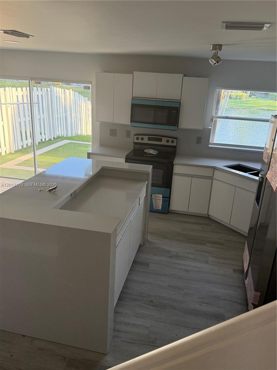 A kitchen features white cabinets, a quartz island, and a view of a backyard canal — 13950 Oak Ridge Dr, Davie FL 33325, DAVIE, FL