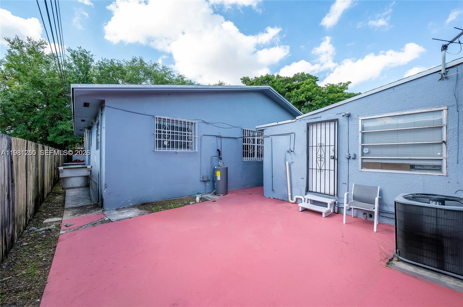A blue house exterior features a red concrete patio, a water heater, and security bars — 2610 NW 33rd St, Miami FL 33142, MIAMI, FL