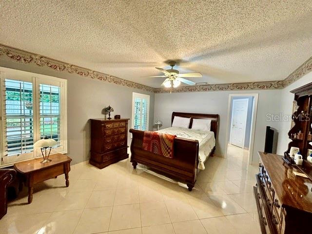 A bedroom features a wooden bed, a dresser, a side table, and a ceiling fan — 15116 ROUNDUP DRIVE, TAMPA, FL