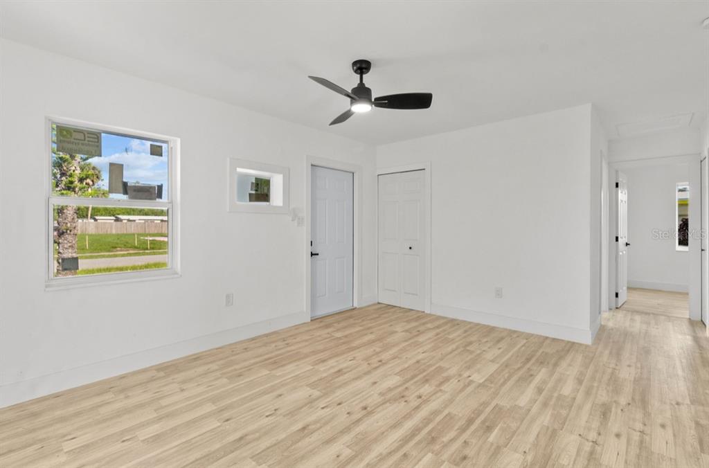 A bright room features white walls, light wood-look flooring, a ceiling fan, and a window — 2352 EDNOR STREET, PORT CHARLOTTE, FL