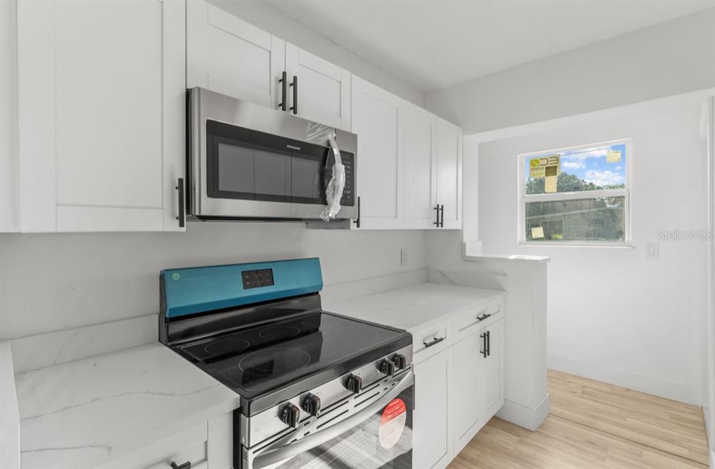 A kitchen features white cabinets, stainless steel appliances, and light-colored countertops — 2352 EDNOR STREET, PORT CHARLOTTE, FL