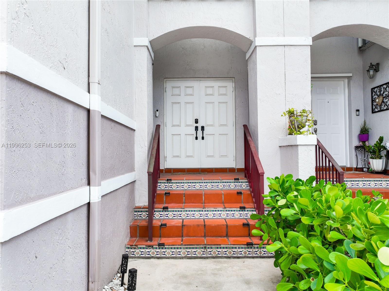 A set of tiled steps with decorative risers leads to a white double-door entryway — 10101 SW 154th Cir Ct # 107, Miami FL 33196, MIAMI, FL