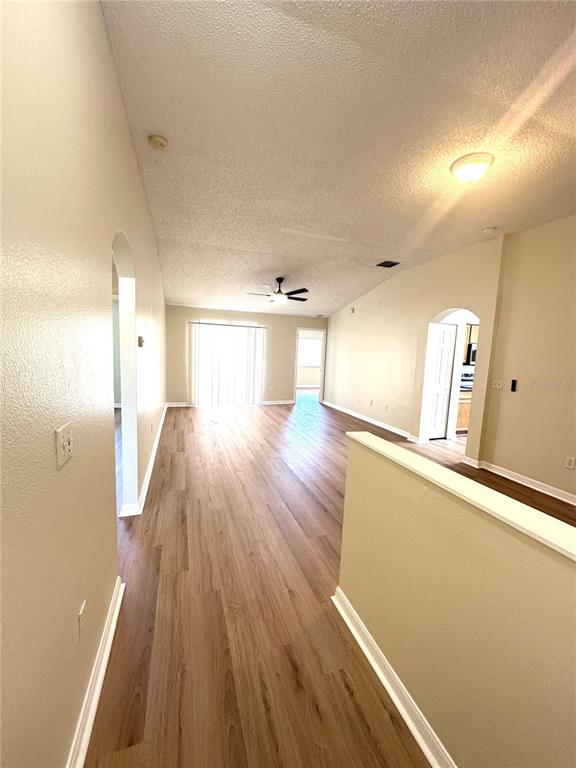 An interior view of a living area with wood-look flooring, vaulted ceilings, and arched doorways — 11030 WHITTNEY CHASE DRIVE, RIVERVIEW, FL