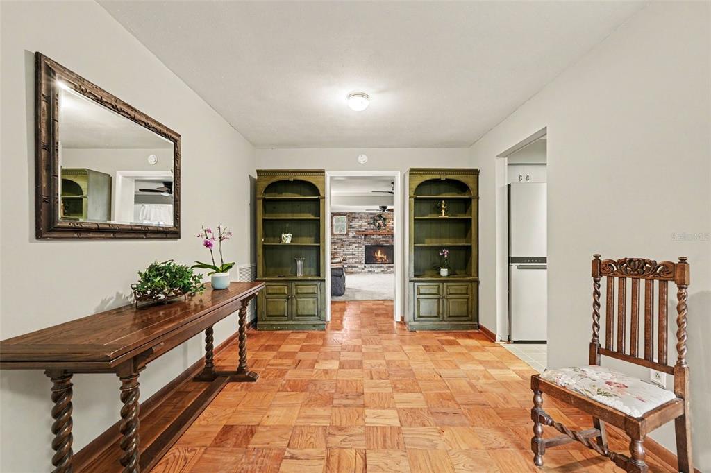A foyer with parquet wood flooring, a wooden console table, two bookcases, and a chair — 10308 N OAKLEAF AVENUE, TAMPA, FL