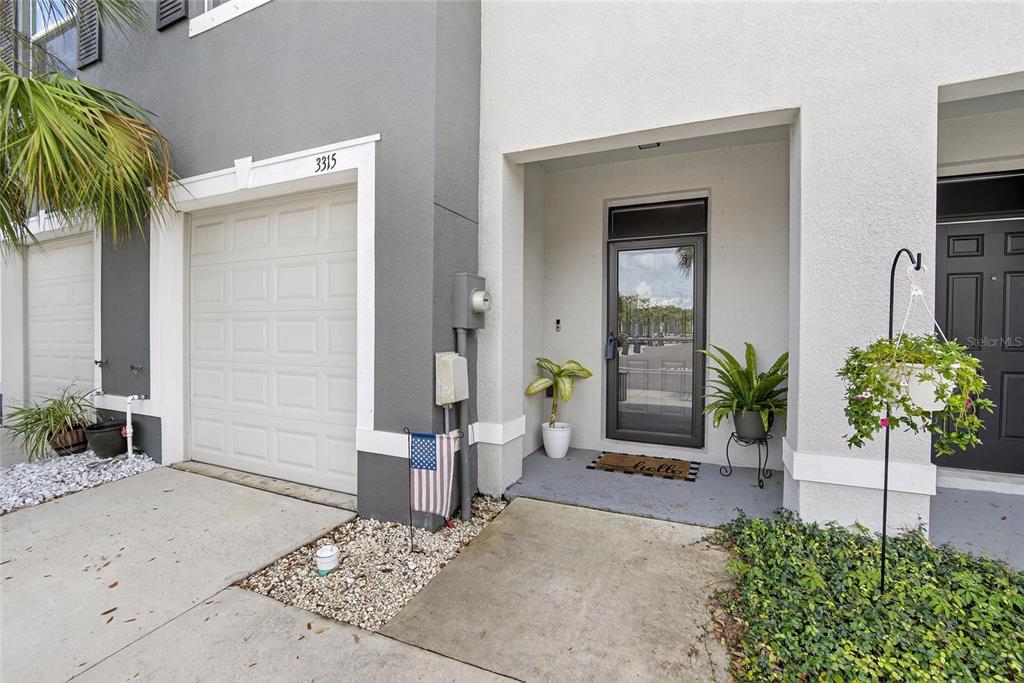 The exterior of a townhouse features a garage, a covered entryway, and a small garden — 3315 PLEASANT WILLOW COURT, BRANDON, FL