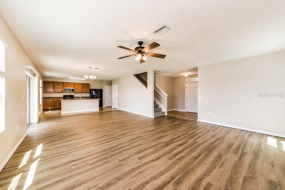 An open-concept living area features wood-look flooring, a ceiling fan, and a kitchen with cabinets — 204 LONE DOVE LANE, BRADENTON, FL