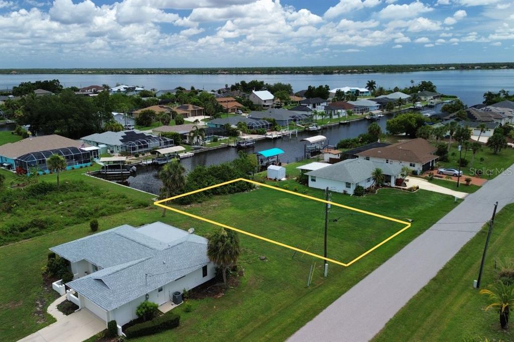 An aerial view shows a vacant rectangular waterfront lot outlined in yellow near a canal — 12350 QUINLAN AVENUE, PORT CHARLOTTE, FL
