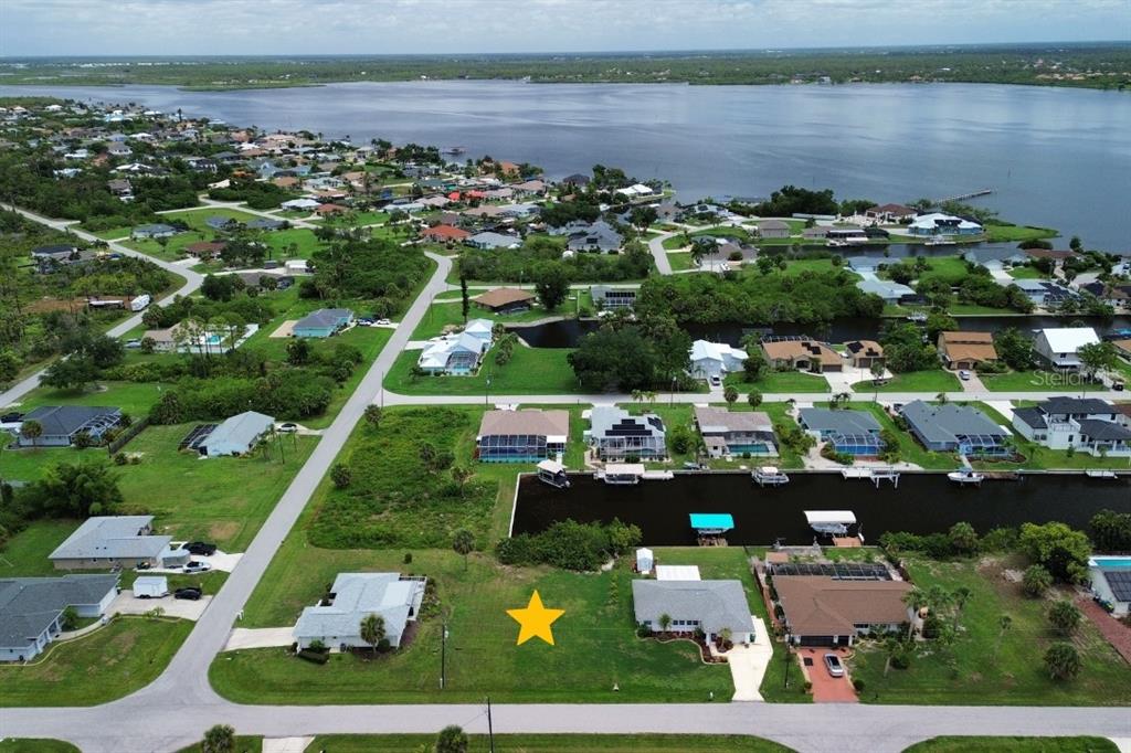 An aerial view shows a vacant residential lot marked with a yellow star near water — 12350 QUINLAN AVENUE, PORT CHARLOTTE, FL