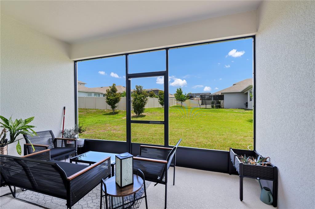 A screened-in patio features outdoor furniture, a small planter, and a view of a backyard — 4480 LIONS GATE AVENUE, CLERMONT, FL