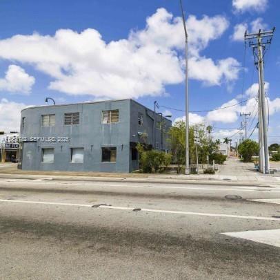 A two-story, blue-painted commercial building stands along a road under a partly cloudy sky — 8201 Biscayne Blvd, Miami FL 33138, MIAMI, FL