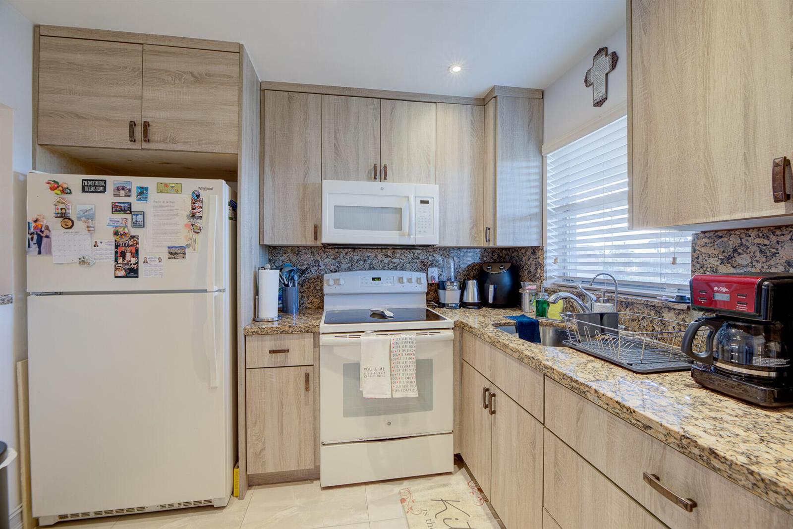A kitchen features light wood cabinets, granite countertops, a white stove, and a white refrigerator — 6850 Royal Palm Boulevard # 303g, Margate FL 33063, MARGATE, FL
