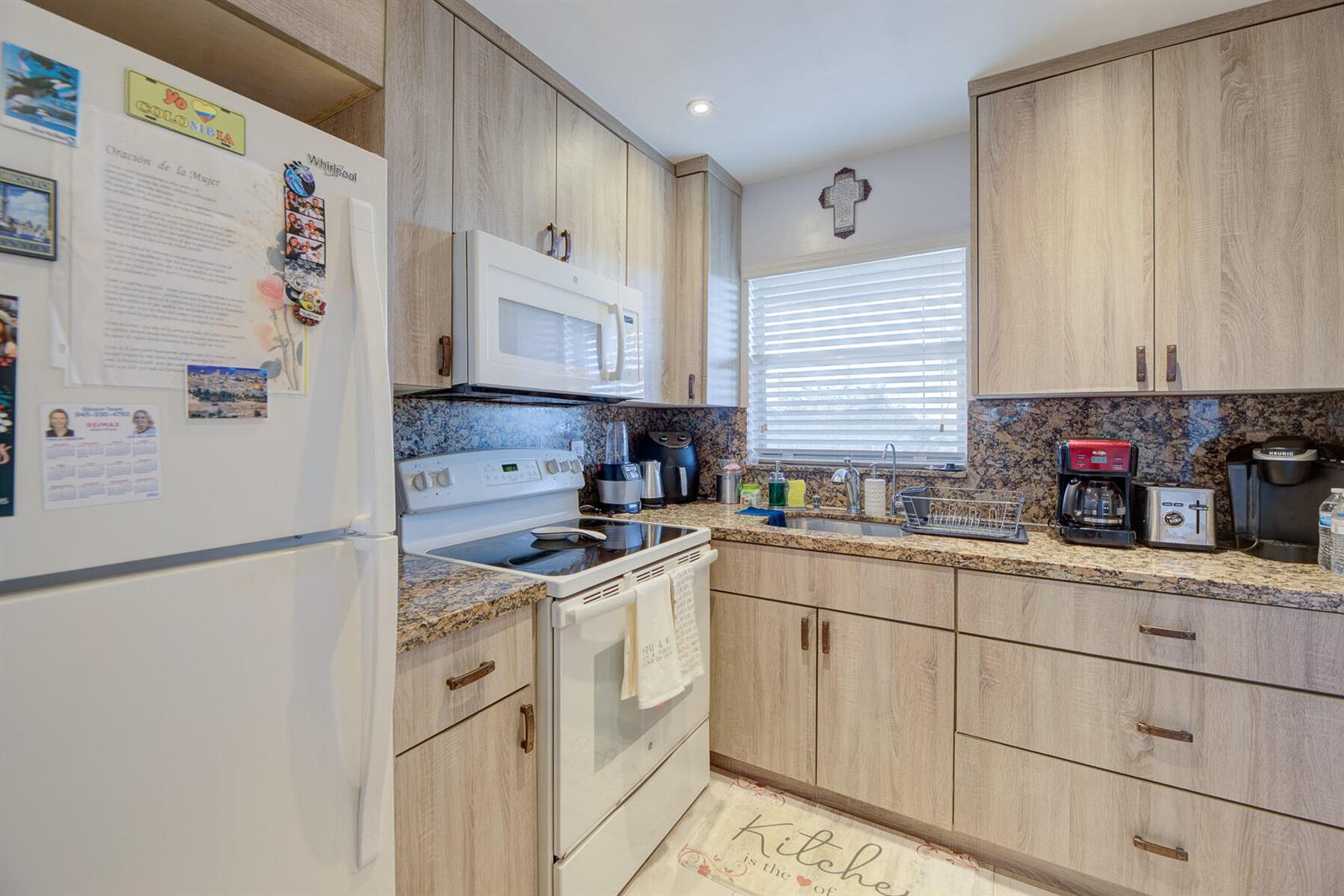 A kitchen features light wood cabinets, granite countertops, and white appliances — 6850 Royal Palm Boulevard # 303g, Margate FL 33063, MARGATE, FL