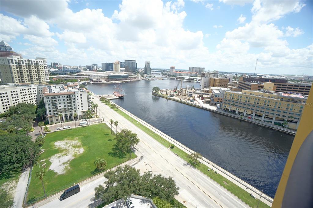 An elevated view of a riverfront cityscape featuring buildings, a road, and a docked ship — 345 BAYSHORE BOULEVARD UNIT 1810, TAMPA, FL