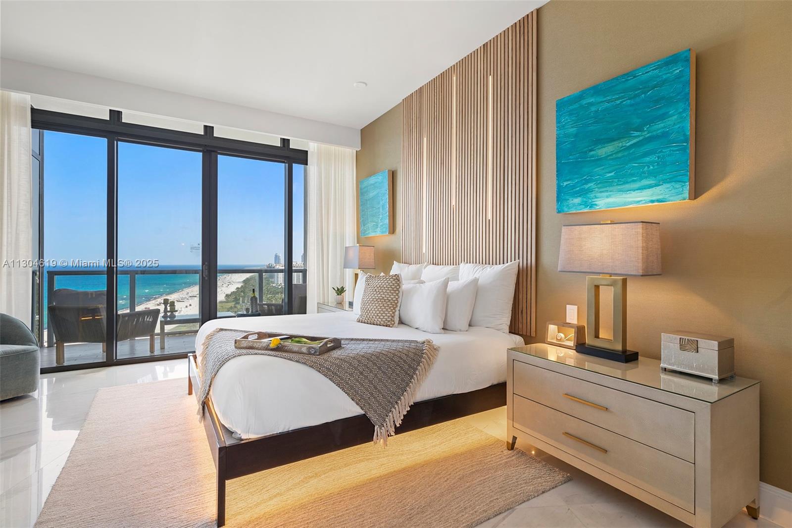 A modern bedroom features a wood-slatted headboard, ocean views, and a balcony with outdoor seating — 2201 Collins Ave, Miami Beach FL 33139, MIAMI BEACH, FL