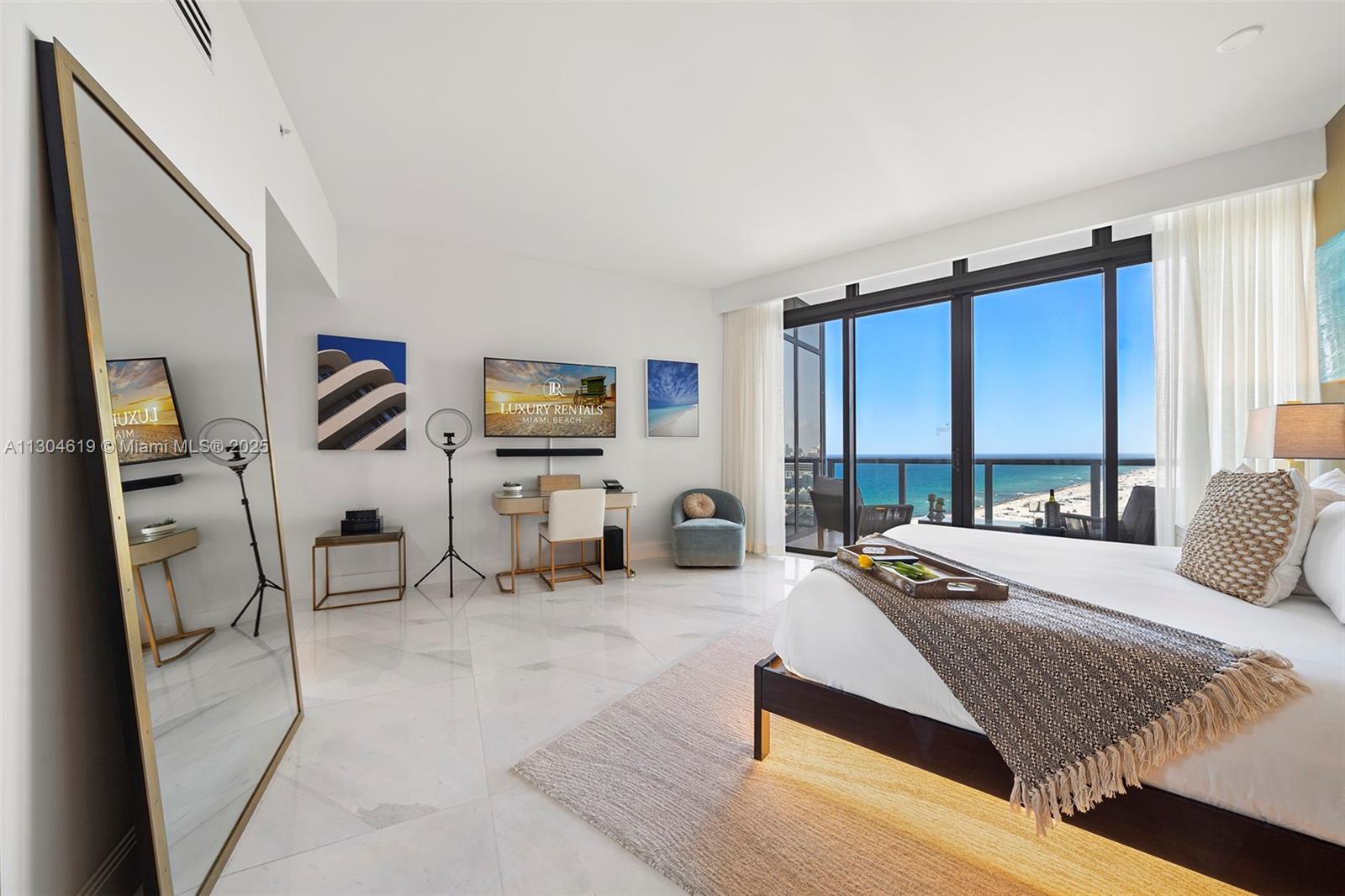 A bedroom with marble floors, a large mirror, and a balcony overlooking the ocean — 2201 Collins Ave, Miami Beach FL 33139, MIAMI BEACH, FL